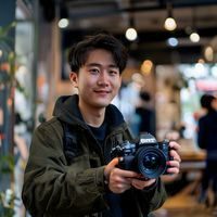 摄影教学博主陈小野，男生手持相机在咖啡馆内讲解偷拍自拍构图技巧，笑容亲切